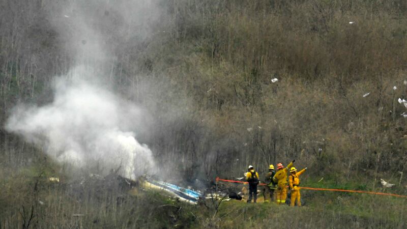 FILE - Firefighters work the scene of a helicopter crash where former NBA basketball star Kobe...