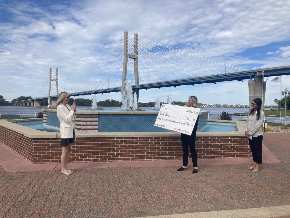 Officials with QMG present the check for this year's race to YWCA Quincy executive director...